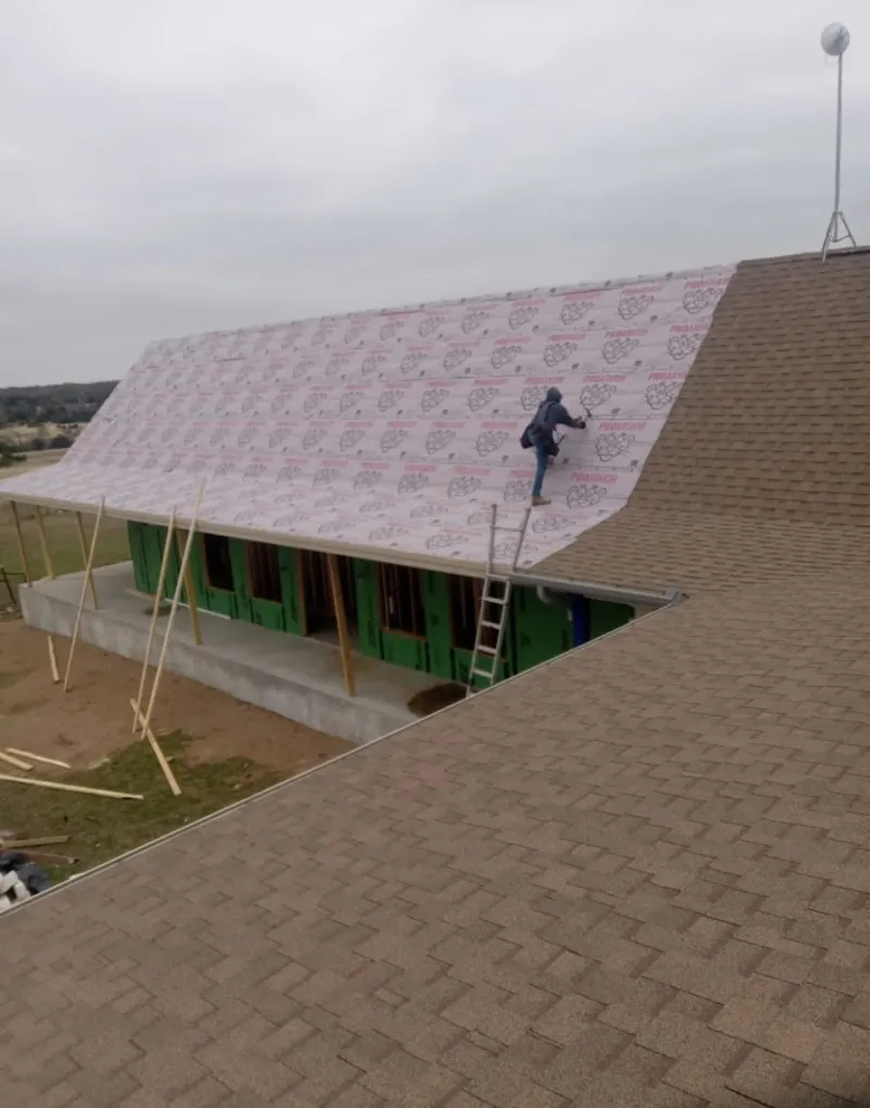 Worker preparing underlayment for a metal roof installation in East Milton
